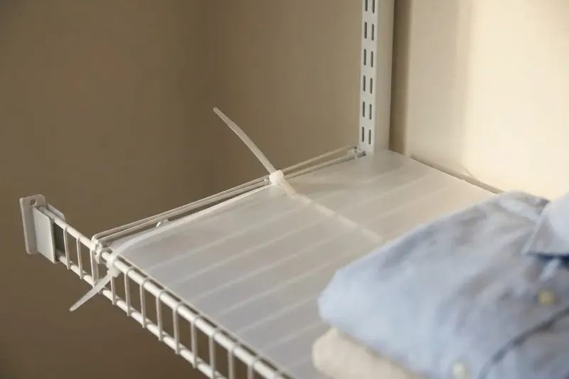 A drop-in shelf liner fastened to wire shelving with a clear nylon zip tie.